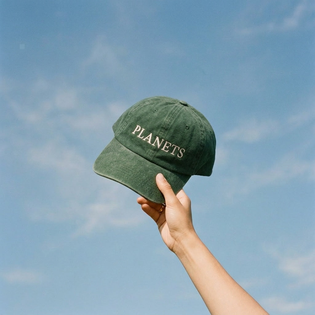 Green cap with 'PLANETS' text held against a blue sky astrology gift dad cap 